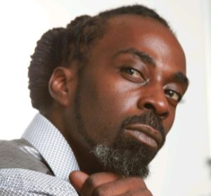 Jibril M. Waajid, natural hair specialist and team member at Nappy Hutt LLC, in a professional headshot.